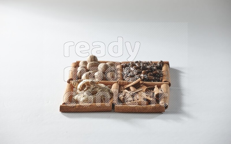 4 squares of cinnamon sticks full of coffee beans, nutmeg, cinnamon and dried ginger on white flooring