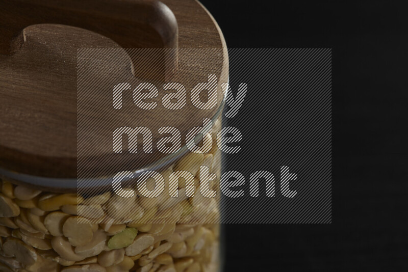 Crushed beans in a glass jar on black background