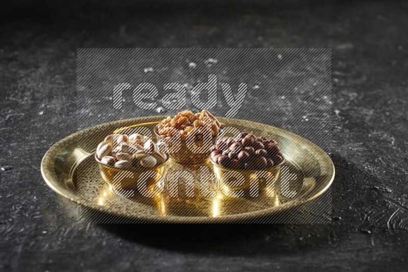 Nuts in metal bowls on a tray in a dark setup