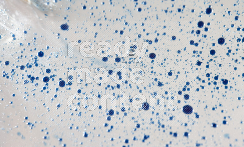 لقطات مقربة لقطرات ألوان مائية زرقاء على سطح الزيت على خلفية بيضاء