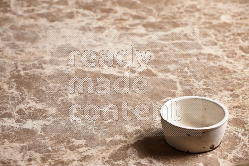 A white pottery bowl on beige marble background