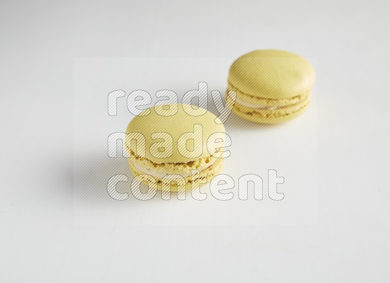 45º Shot of two Yellow Lime macarons on white background