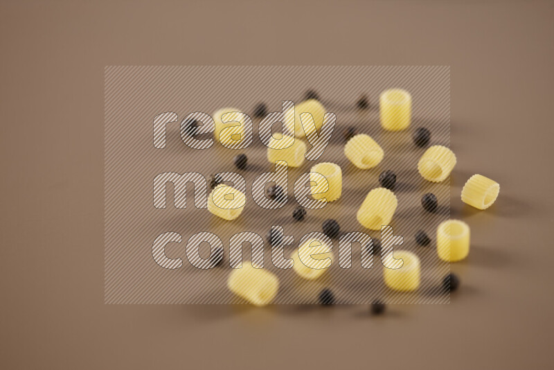 Raw pasta with different ingredients such as cherry tomatoes, garlic, onions, red chilis, black pepper, white pepper, bay laurel leaves, rosemary and cardamom on beige background
