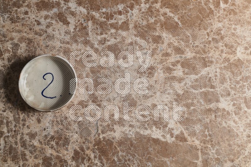 A multicolored pottery bowl on beige marble background