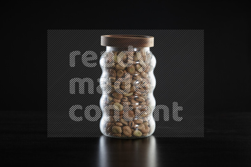 Fava beans in a glass jar on black background