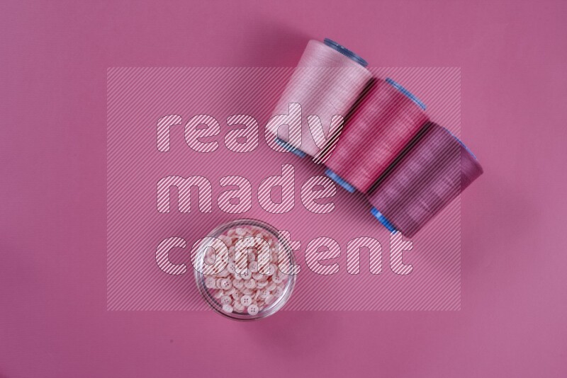 A pink collection of sewing and tailoring tools arranged on a pink background