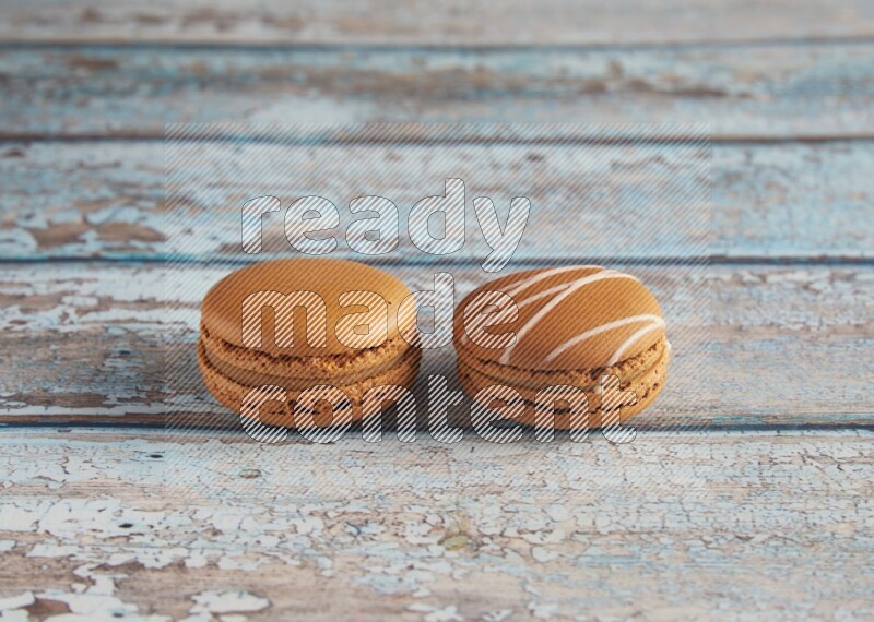 45º Shot of of two assorted Brown Irish Cream, and Brown Maple Taffy macarons  on light blue background