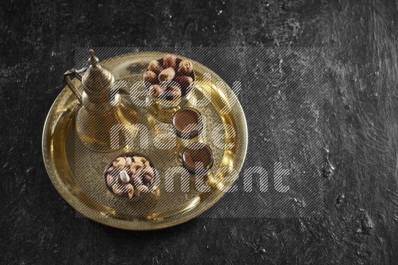 Nuts with dates and a drink on a metal tray in a dark setup