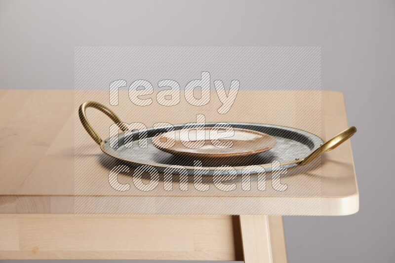 multicolored plate placed on a rounded stainless steel tray with golden handels on the edge of wooden table