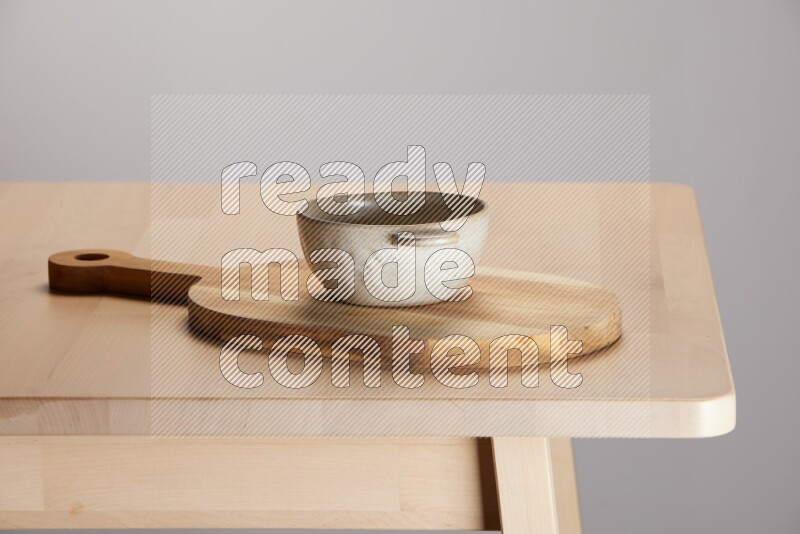 off white bowl placed on a  wooden oval cutting board on the edge of wooden table