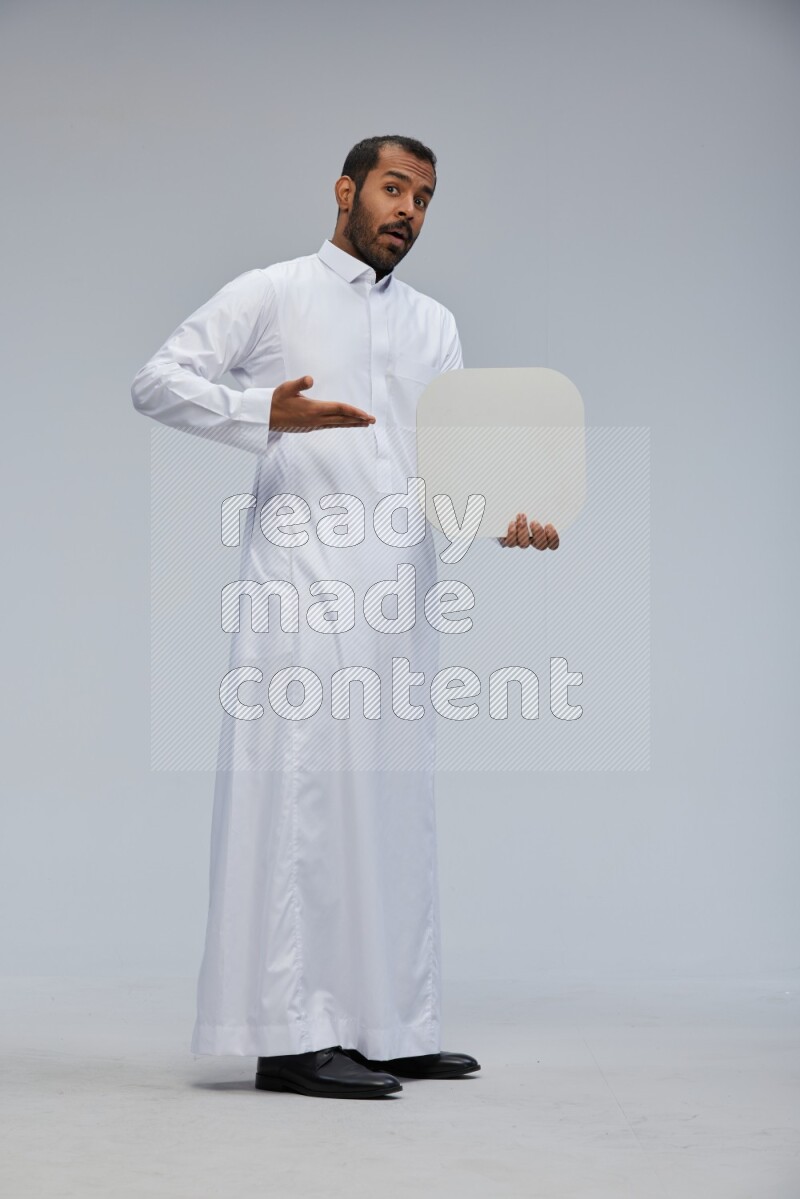 Saudi man wearing Thob standing holding social media sign on Gray background