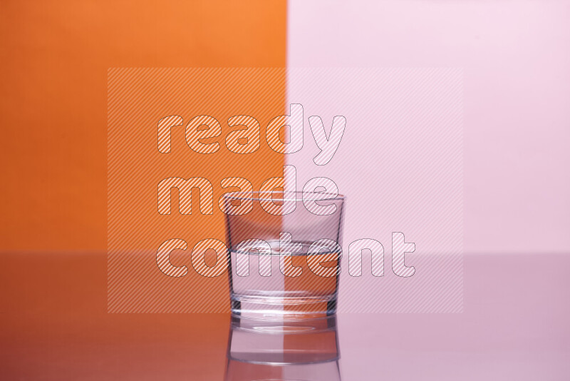 The image features a clear glassware filled with water, set against orange and rose background