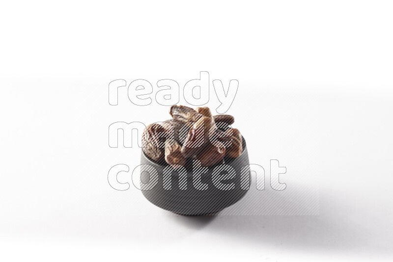 Dates in a black pottery bowl on white background