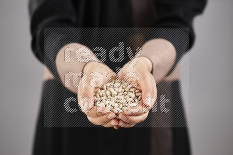 Woman in abaya holding different kinds of legumes in different positions