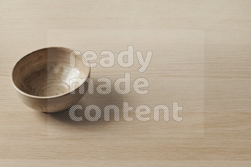 A beige pottery bowl on light wooden background