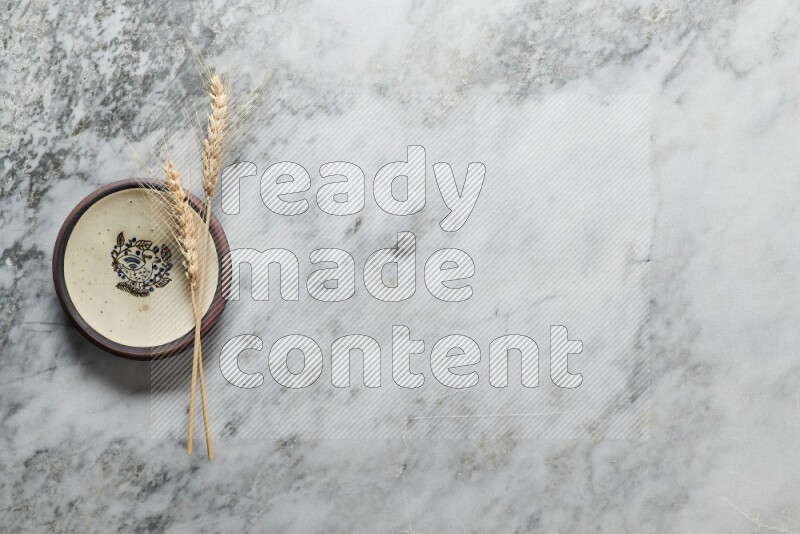 Wheat stalks on decorative pottery plate on grey marble background