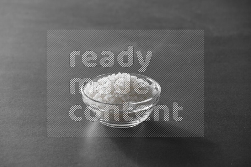 A glass bowl full of salt on black flooring
