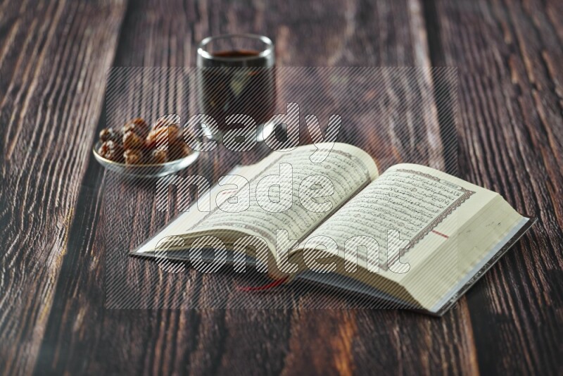 Quran with dates, prayer beads and different drinks all placed on wooden background