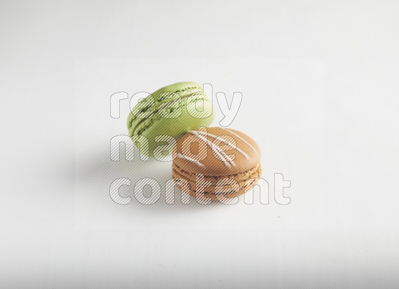 45º Shot of of two assorted Brown Irish Cream, and Green Pistachio macarons on white background