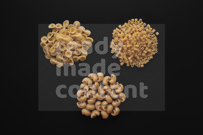 Different pasta types in bunches on black background