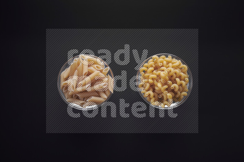 Different pasta types in glass bowls on black background