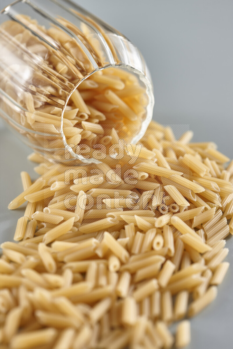 Flipped jar full of raw pasta on light blue background