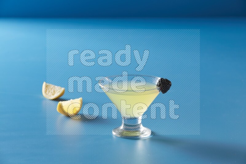 glass of lemon juice with berry on blue background