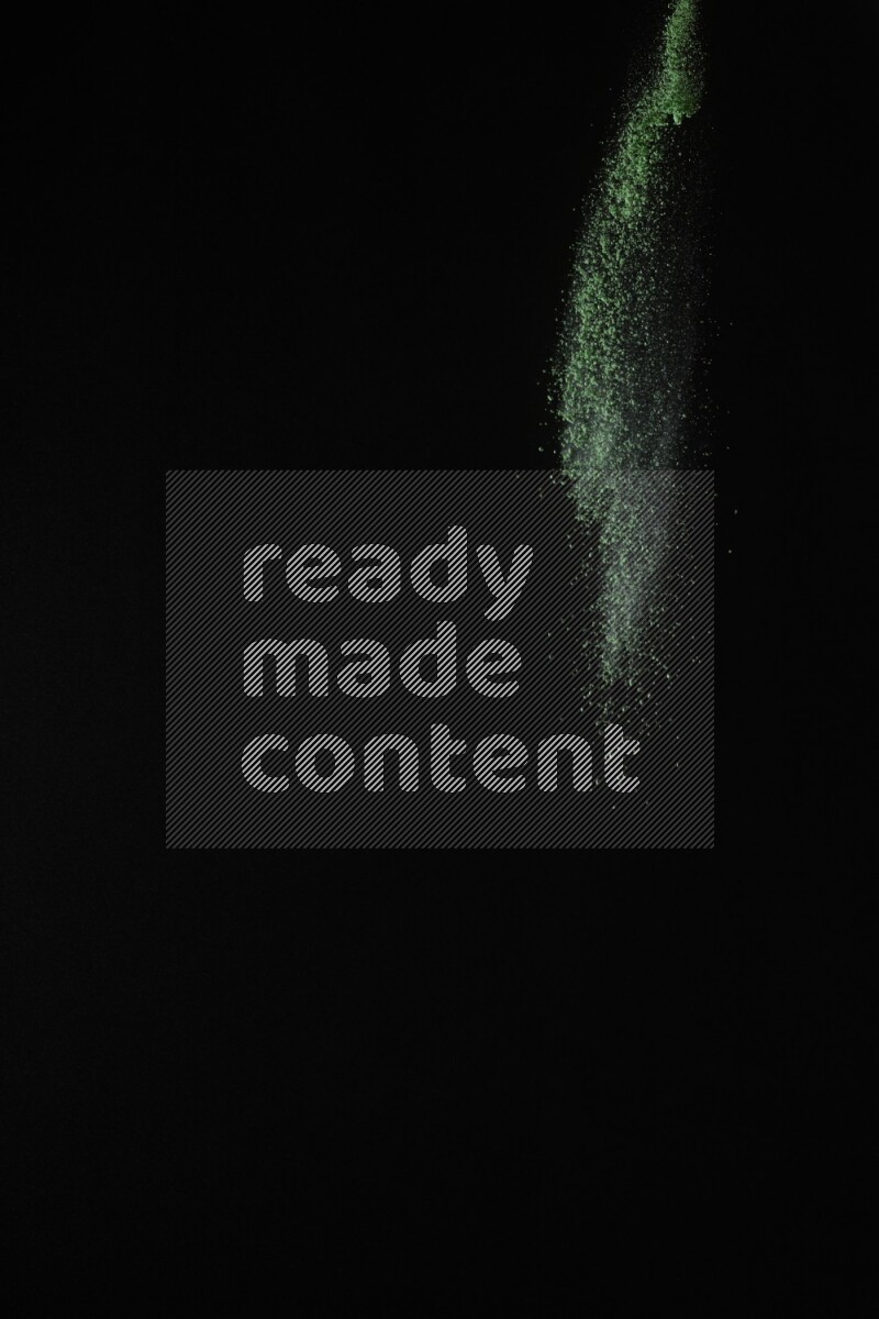 A side view of green powder explosion on black background