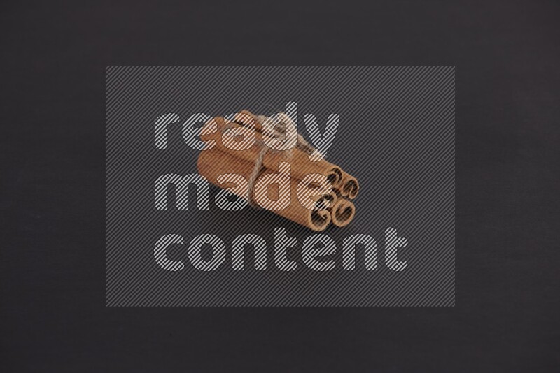 4 أعواد من القرفة مربوطة علي خلفية سوداء