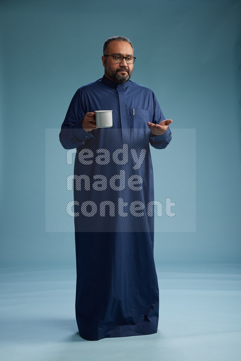 Saudi Man without shimag Standing drinking coffee on blue background