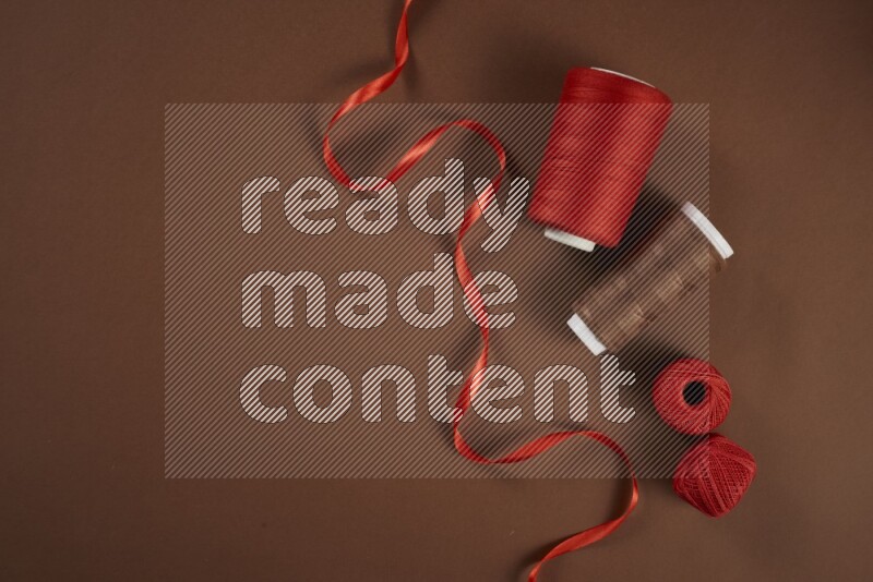 A red collection of sewing and tailoring tools arranged on a brown background