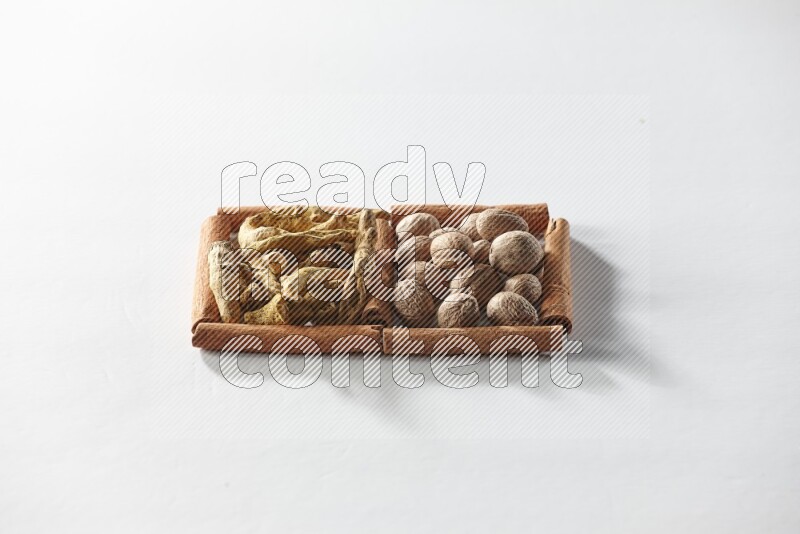 مربعان من أعواد القرفة ممتلئان بأصابع الكركم  وجوزة الطيب علي خلفية بيضاء