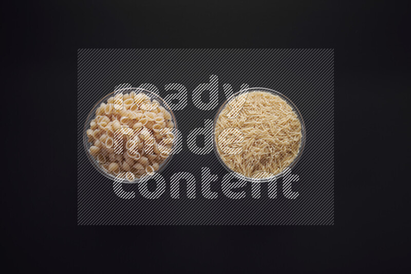 Different pasta types in glass bowls on black background