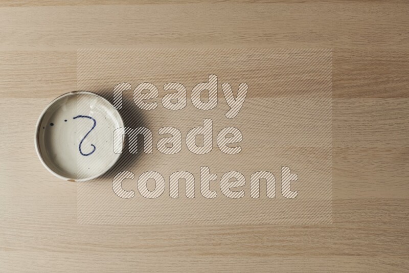 A multicolored pottery bowl on light wooden background