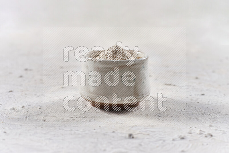 A beige pottery bowl full of onion powder on white background