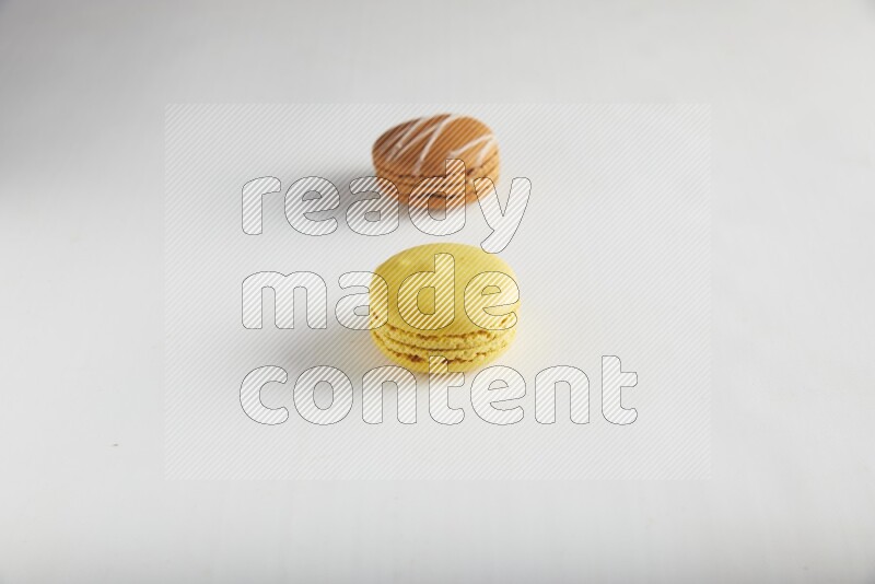 45º Shot of of two assorted Brown Irish Cream, and Yellow Lemon macarons on white background