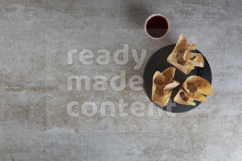 wonton cups with soy sauce ramkin on circle slate on grey textured counter top