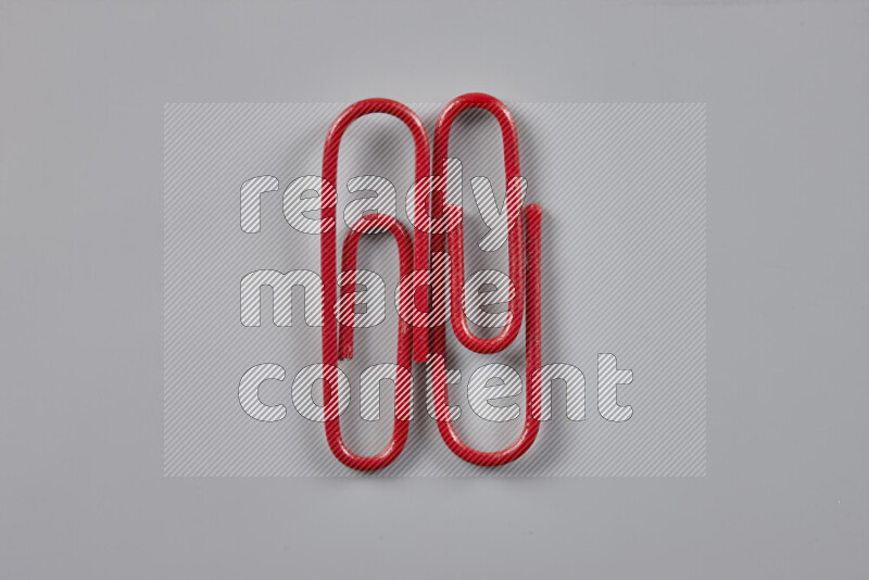 Red paper clips isolated on a grey background