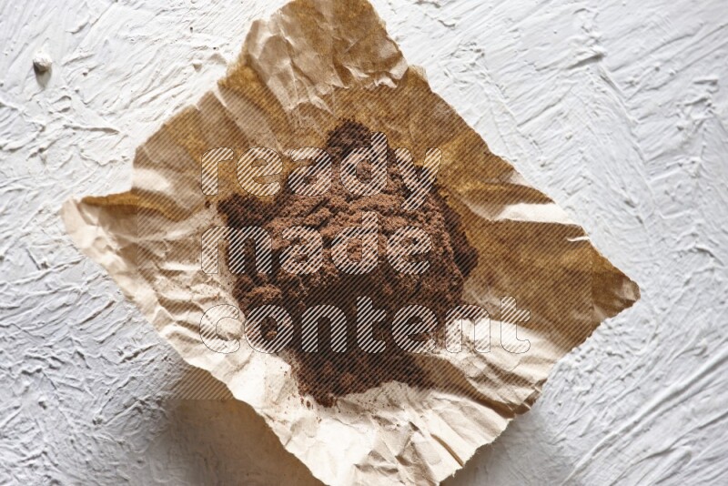 Cloves powder on crumpled piece of paper on a textured white flooring