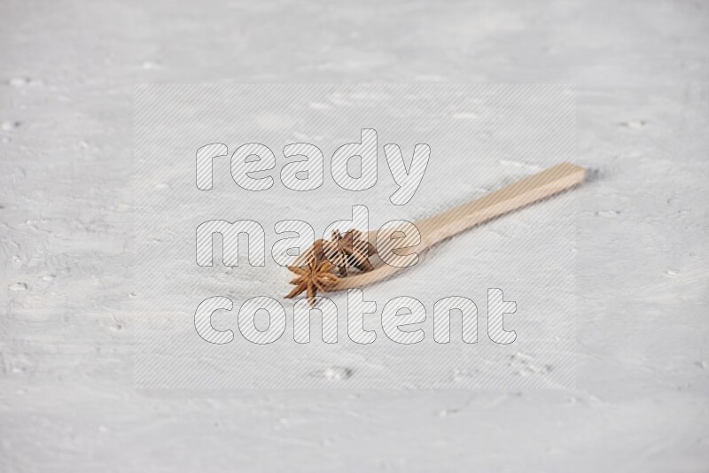 Star Anise in a wooden spoon on white flooring