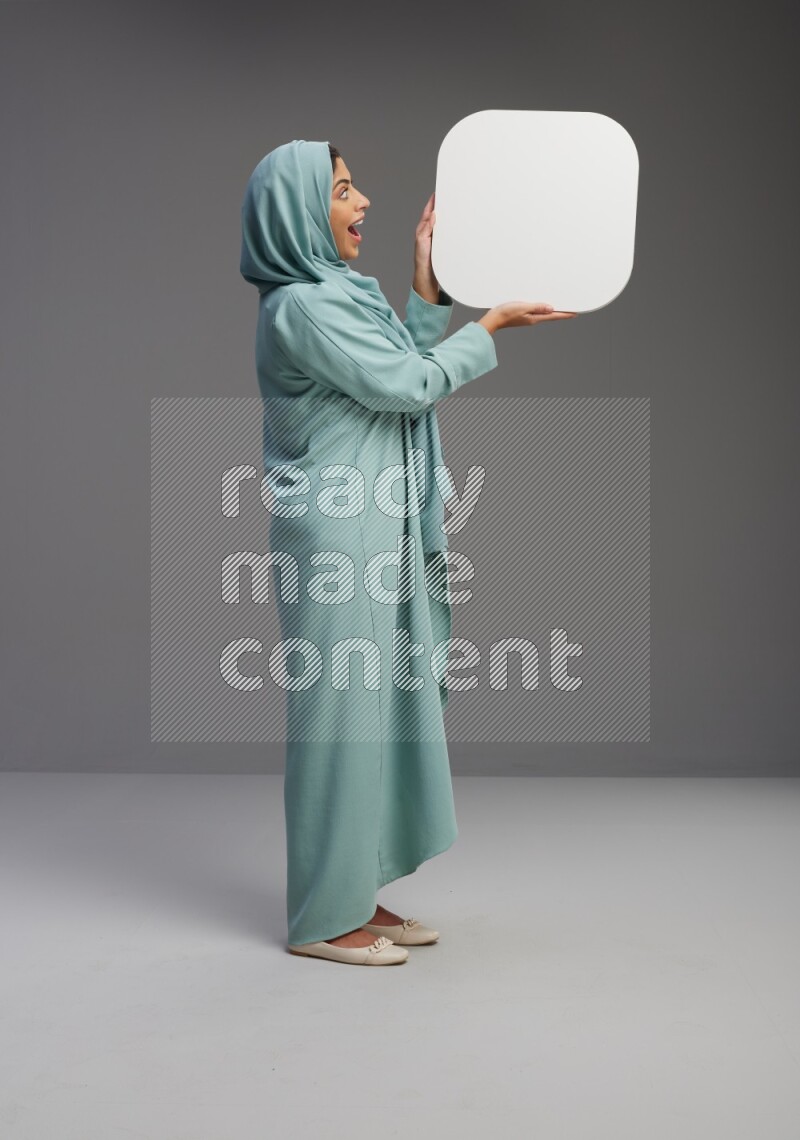 Saudi Woman wearing Abaya standing holding social media sign on Gray background