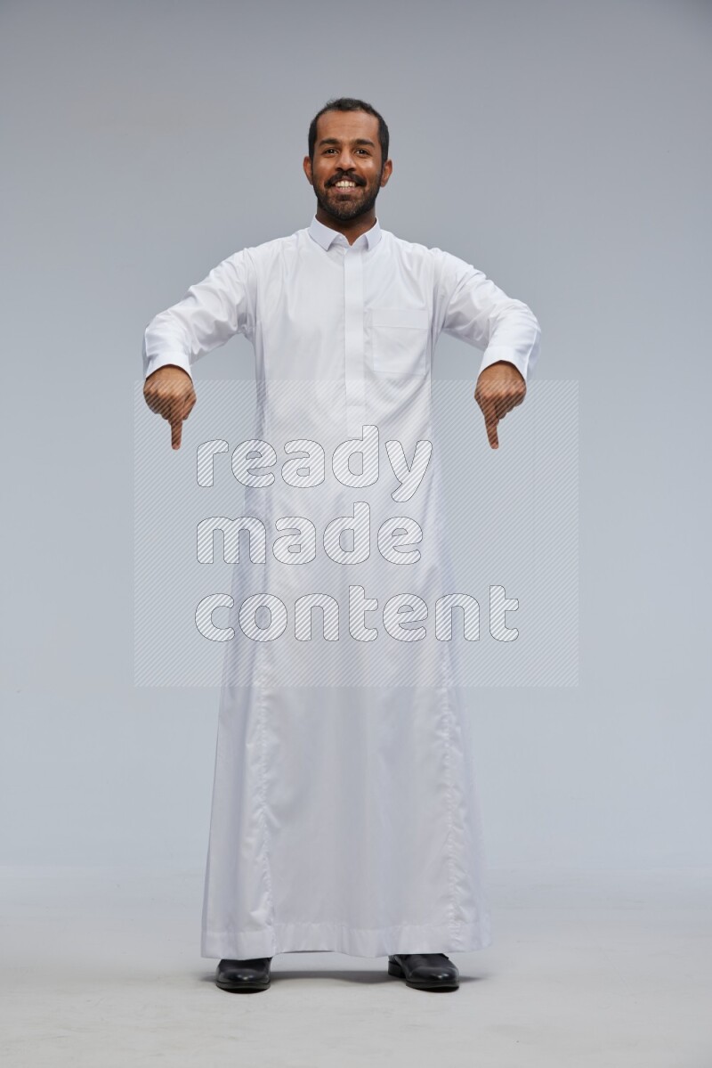 Saudi man Wearing Thob standing interacting with the camera on Gray background
