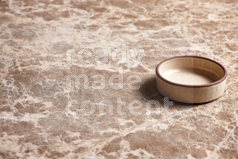 A beige pottery oven plate on beige marble background