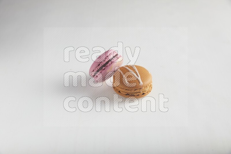 45º Shot of of two assorted Brown Irish Cream, and Purple Strawberry macarons on white background