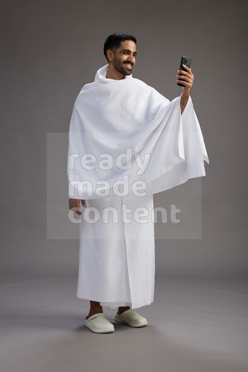 A man wearing Ehram Standing taking selfie on gray background