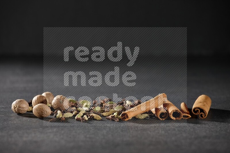 Cardamom, cloves, nutmeg and cinnamon sticks on black flooring