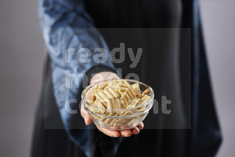 Woman in abaya holding different kinds of snacks in different positions
