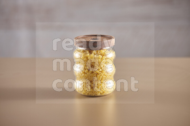 Raw pasta in glass jars on beige background
