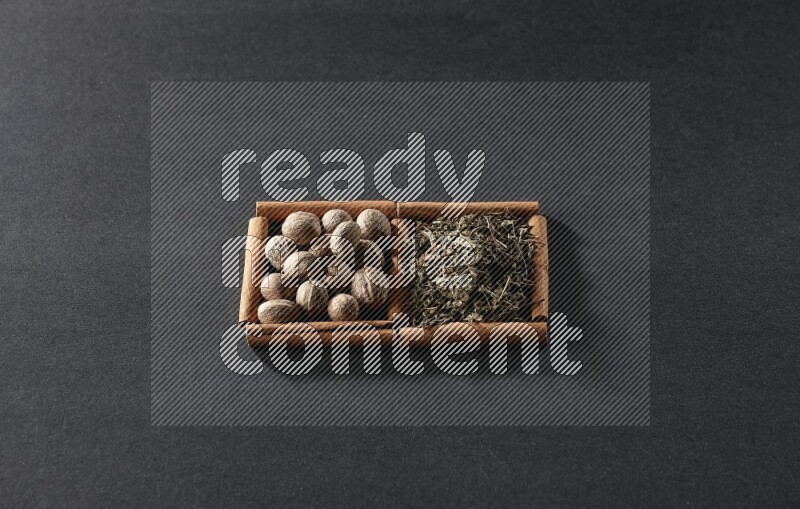 2 squares of cinnamon sticks full of nutmegs and dried basil on black flooring