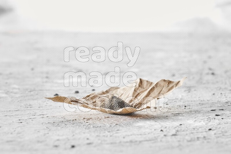 فلفل أسود مطحون في قطعة من الورق علي خلفية بيضاء